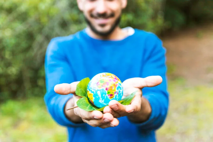 hombre-sosteniendo-globo-con-hoja-verde-y-sonriendo-750x500
